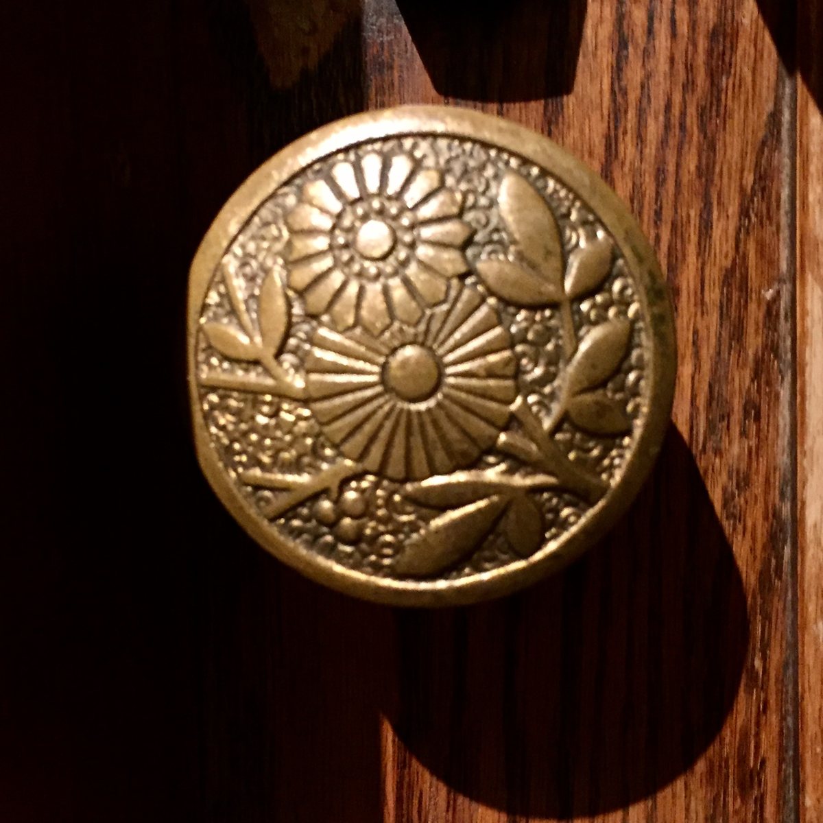 木の扉についた、花の模様の真ちゅうのドアノブ