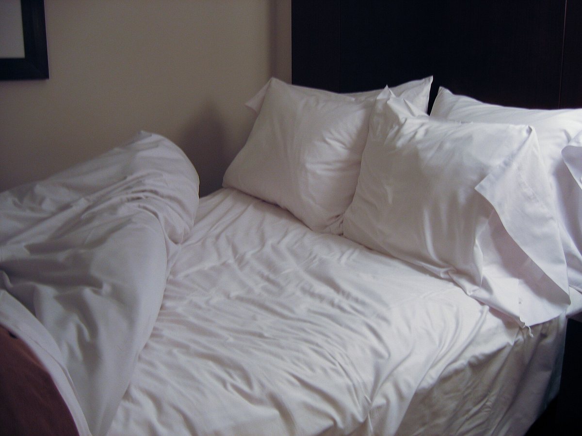 A bed with white pillows and a turned-back comforter