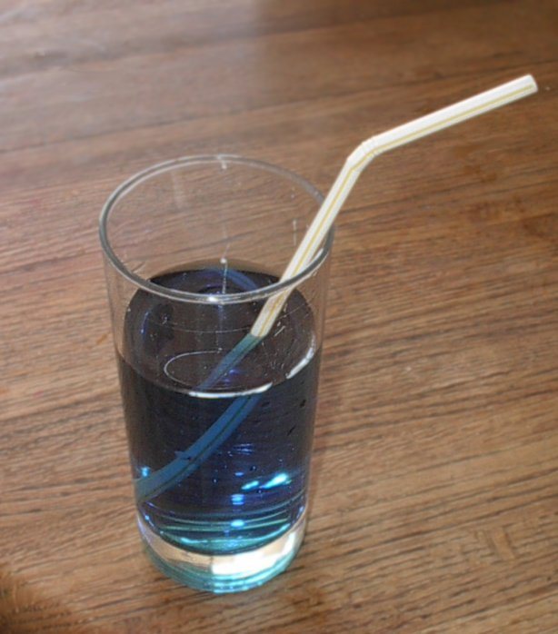 水の入ったコップにななめに入れたストロー。水面のところで折れたように、ずれて見える